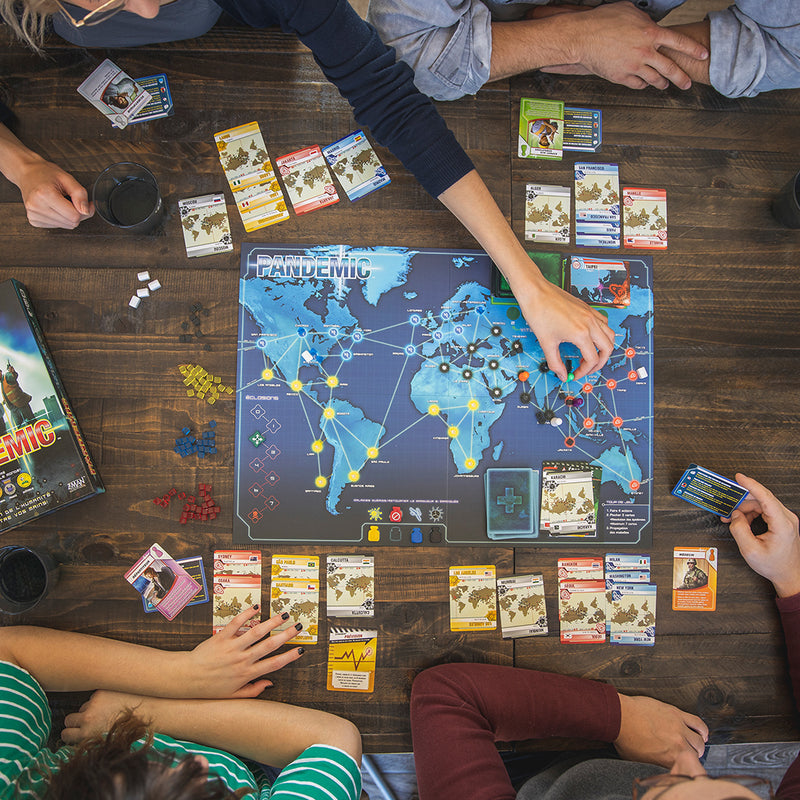 Load image into Gallery viewer, Pandemic Board Game lifestyle image of four people playing game with game contents displayed.