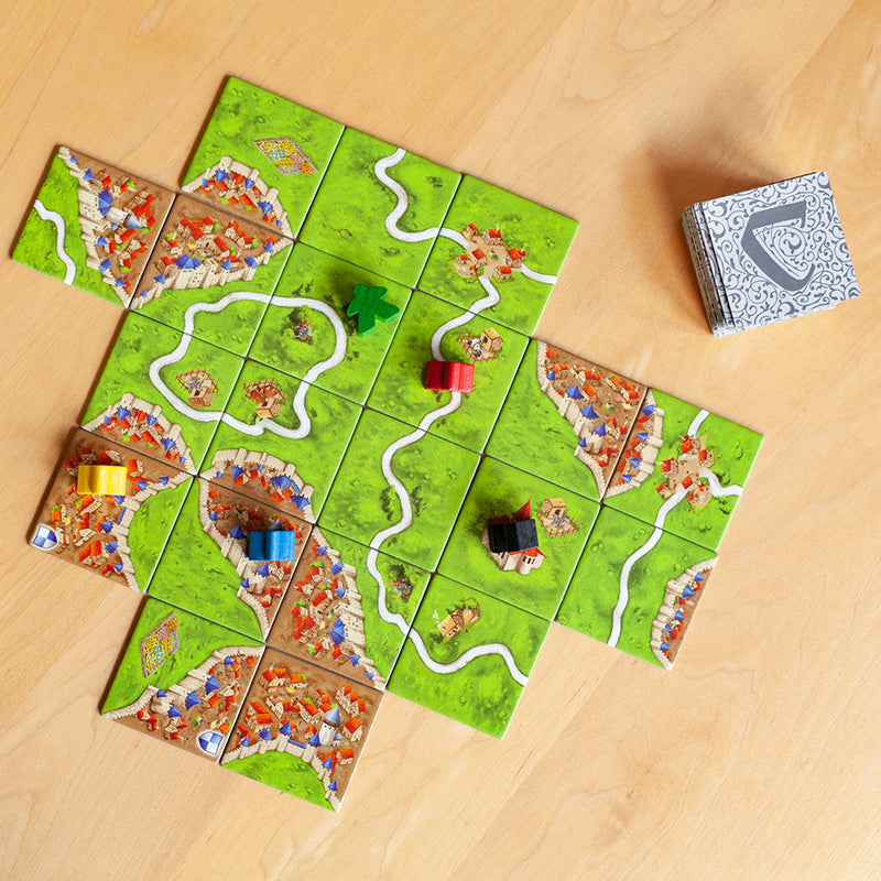 Load image into Gallery viewer, Carcassonne Board Game components including game tiles with land, roads, and cities, and meeples of various colors.