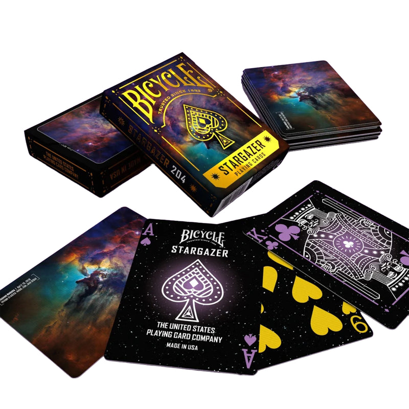 Load image into Gallery viewer, Bicycle Stargazer 204 Playing Cards - view of box and sample cards. Backs of cards feature Lagoon Nebula imagery from Hubble Telescope. Front of cards has space themed art design.
