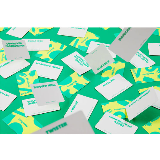 Monikers: Family Edition Party Game - Sample word cards shown including 'Twister' and 'Fish out of Water' cards. 